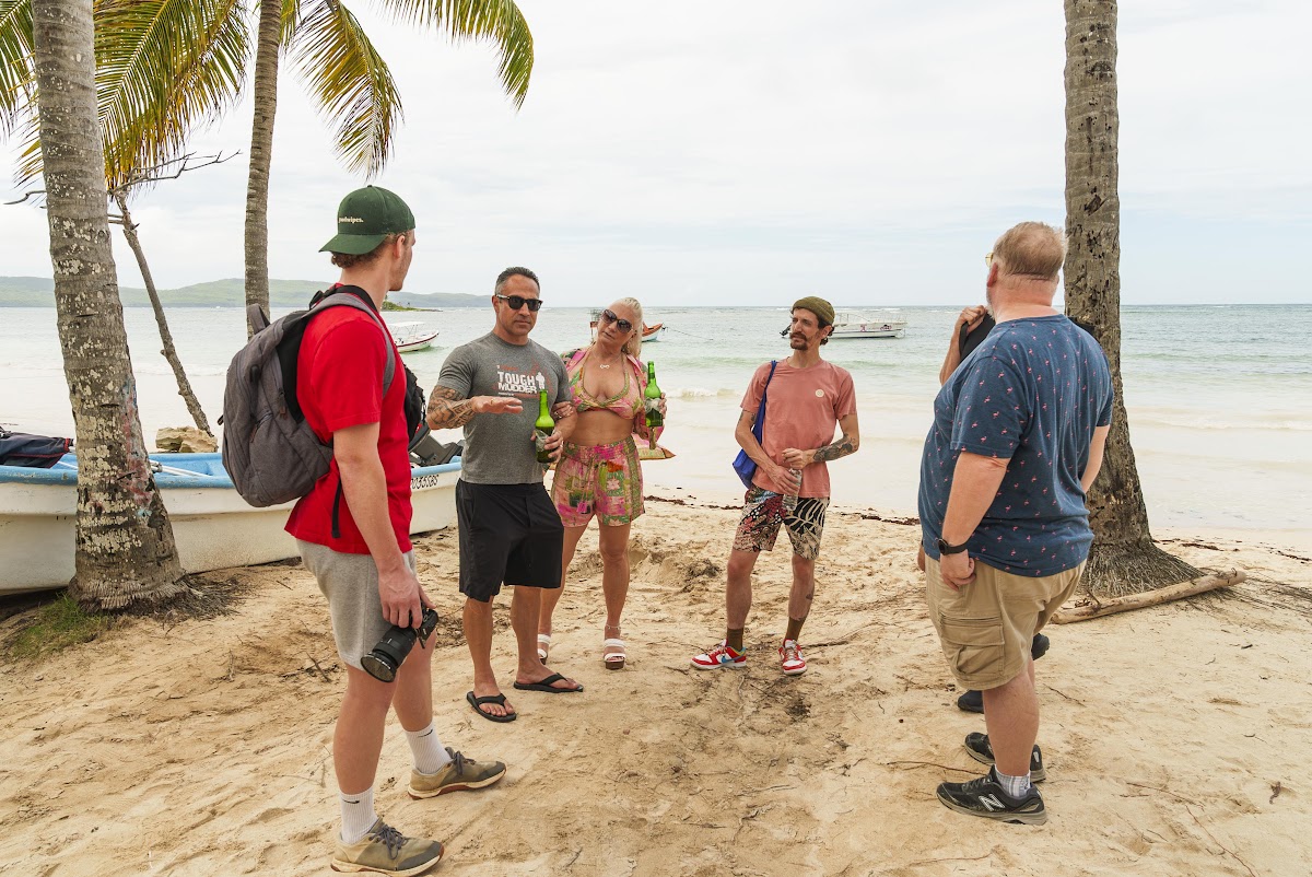 Travelers on the beach beside local boats